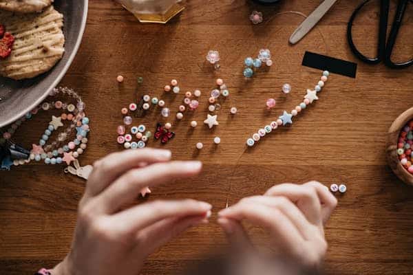 person-placing-beads-on-string-making-bracelet.