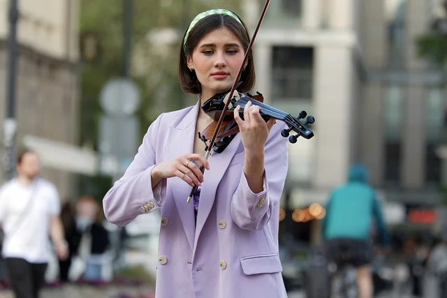 woman-busker-violin-violet suit-blurred background-city